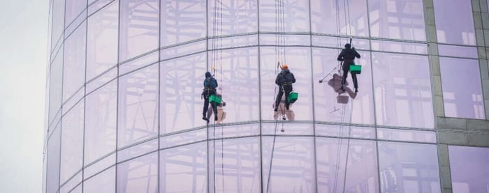 High-rise window cleaner on rope descent system cleaning a glass facade