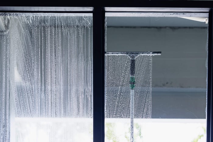 Professional window cleaner using a squeegee on a storefront window