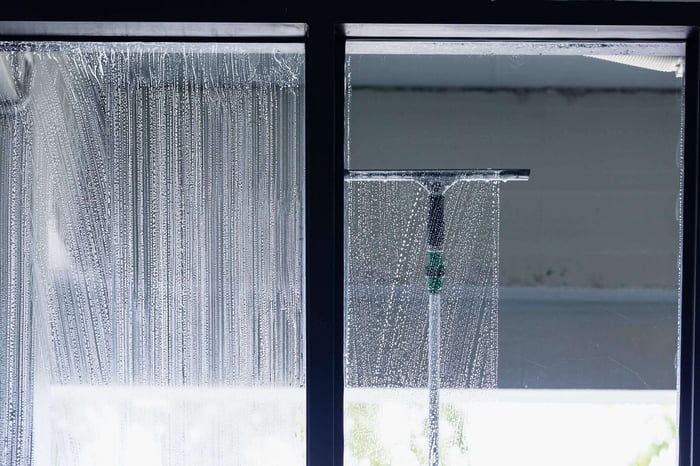 Professional window cleaner using a squeegee on a storefront window