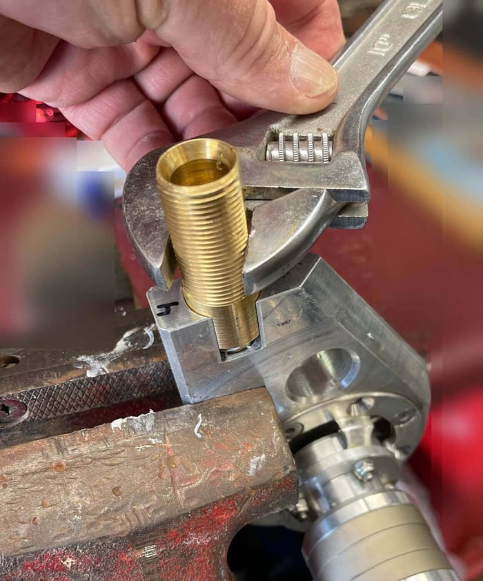 Wrench snugging the brass nozzle assembly back into the aluminum brush housing