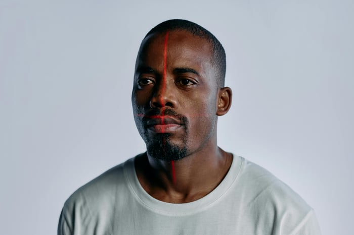 Portrait of an adult man with laser grid on face in studio setting, symbolizing high-tech facial recognition.