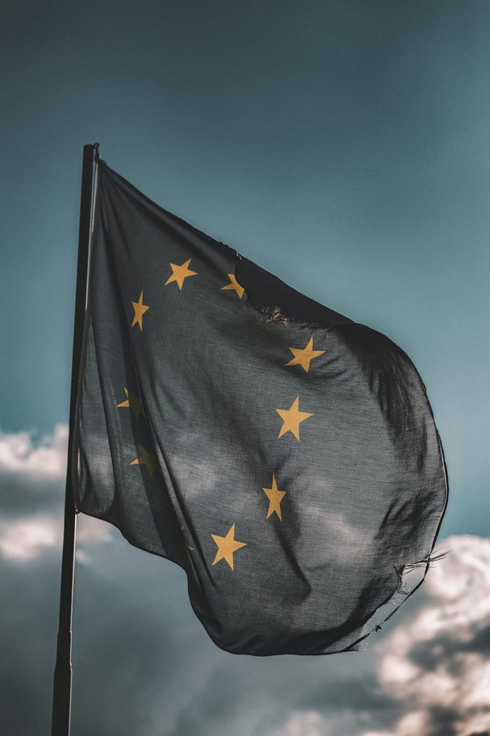European Union flag gently waving on a flagpole against a cloudy sky, symbolizing unity and patriotism.