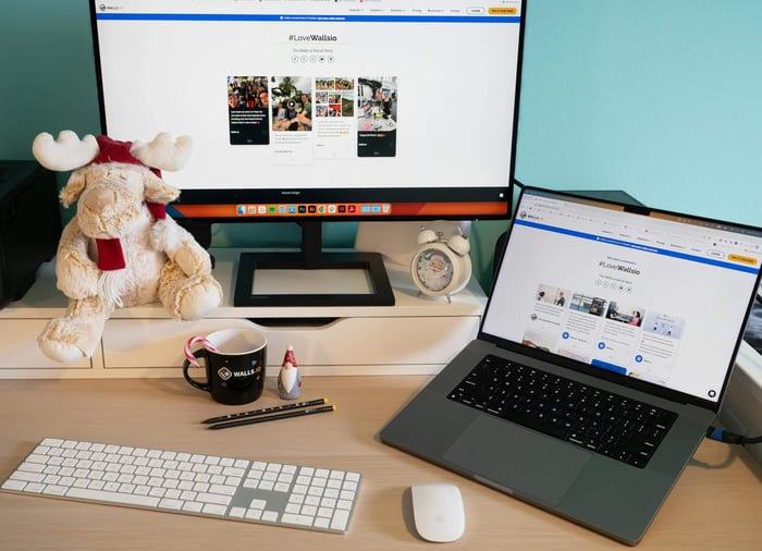 A well-organized home office desk featuring a monitor, laptop, and playful decor for a comfortable workspace.