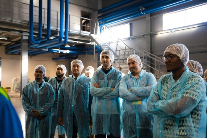 Group of diverse workers wearing blue protective clothing in an industrial setting.