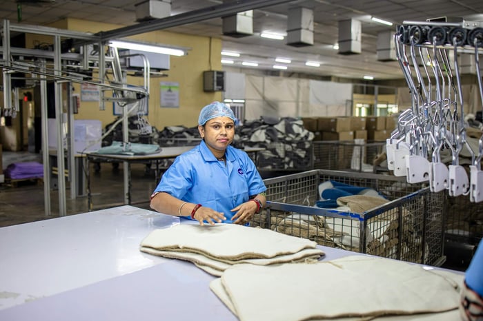 A female worker organizes fabric sheets in a textile factory setting, showcasing industry and diligence.