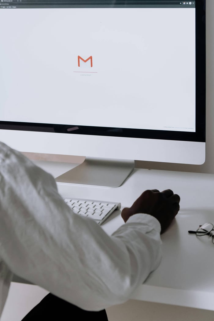 A professional in an office setting checking emails on a desktop computer with a clean workspace.