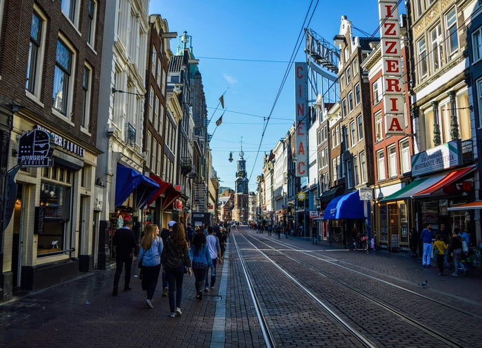 A lively day on Leidsestraat in Amsterdam, with people walking by shops and trams on the street.