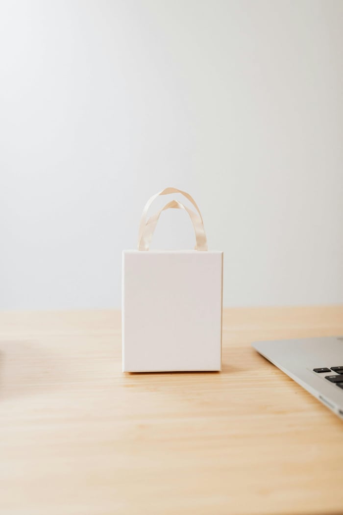 Minimalist white gift box with handle on a wooden table, perfect for packaging or gifting.