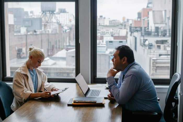 Business meeting between colleagues in a modern office setting with city view.