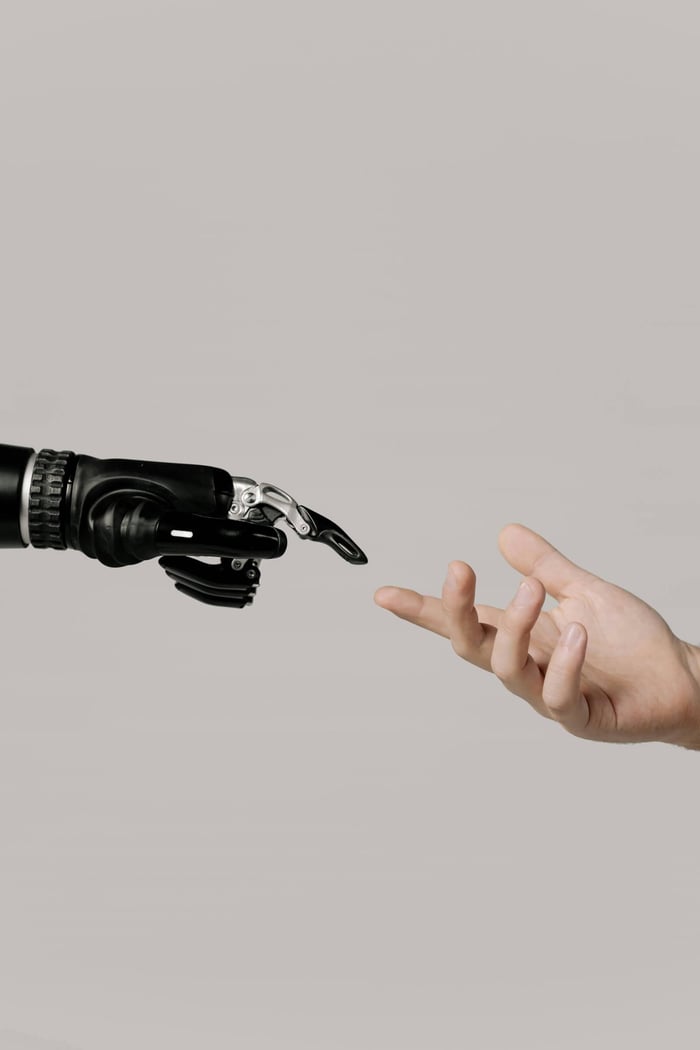 A human hand reaching to touch a bionic prosthetic hand on a white background.