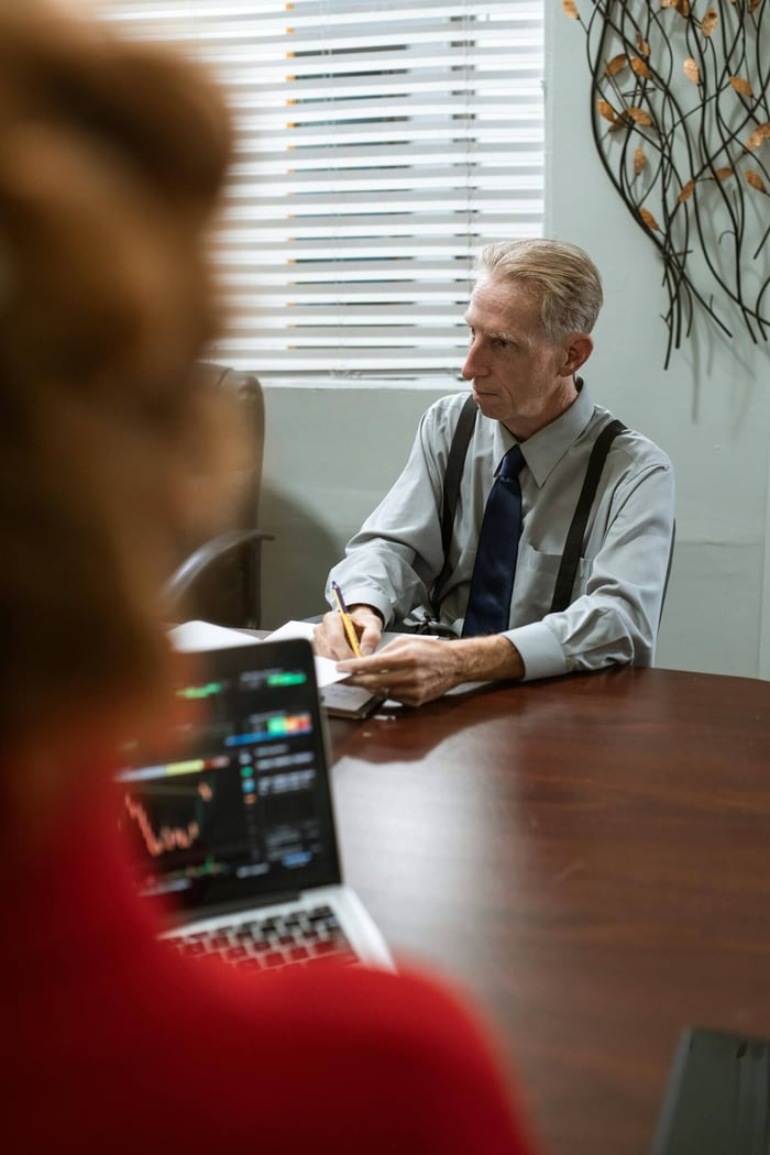 Senior male executive taking notes during a business meeting in a modern office setting.