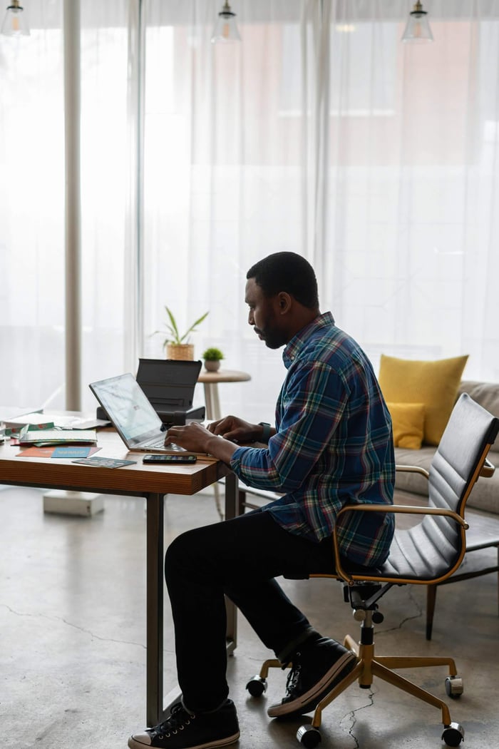 A focused individual working on a laptop in a bright and modern office setting.