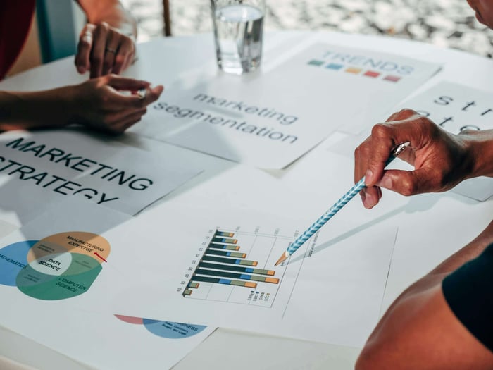 Team working on marketing strategy using data charts and papers in an office meeting.
