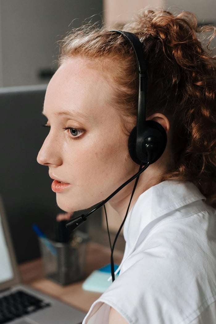 Side view of a woman using a headset while working indoors, conveying focus and professionalism.
