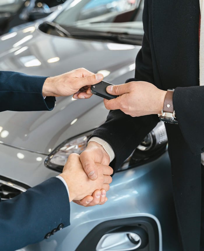 Two men shaking hands after a car purchase.