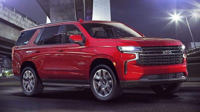Red Chevrolet Tahoe parked at night, with extensive cargo capacity and ride quality, along with a wireless charging pad and third row seating.