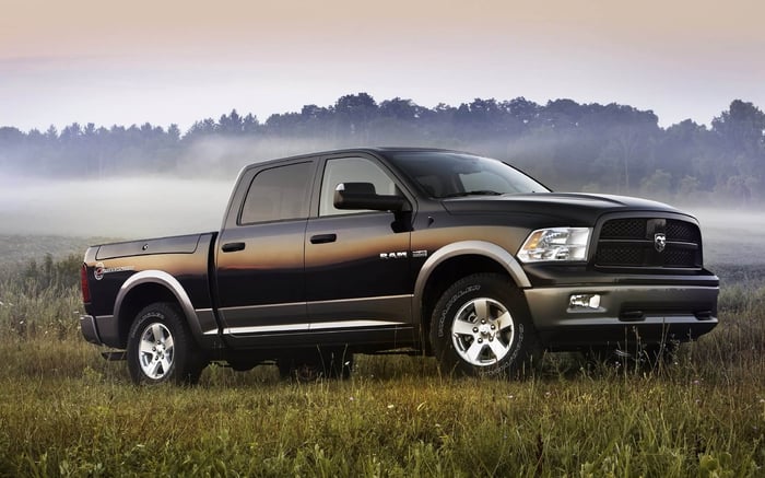 2011 Ram 1500 Outdoorsman Crew Cab in a field of grass with trees in the background.