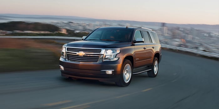 Dark brown Chevrolet Tahoe driving up a hill, with heated steering wheel, rear seats, and 15 mpg city / 20 mpg highway fuel economy.