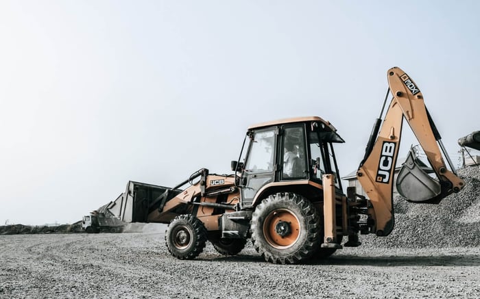Backhoe loader driving at a construction site.