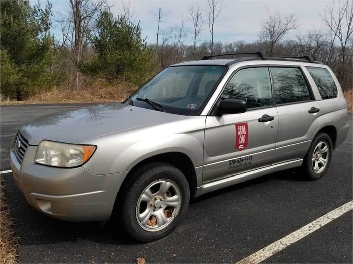 An image of a grey 2007 Subaru Forester, with a red logo of a municipality on one side.