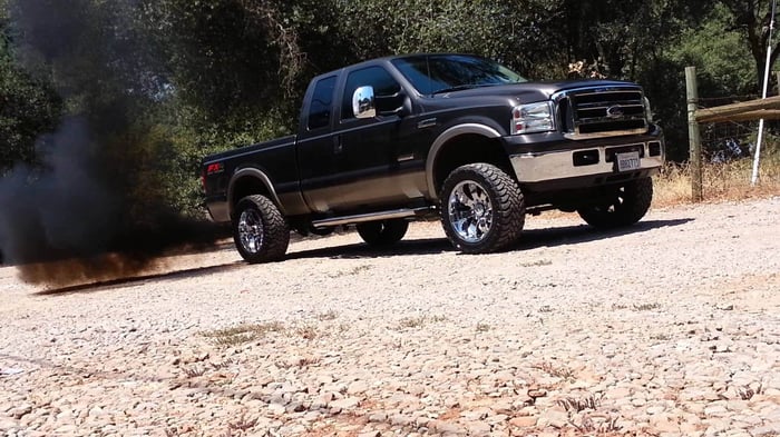 Large black diesel truck with exhaust coming out of the exhaust pipe.