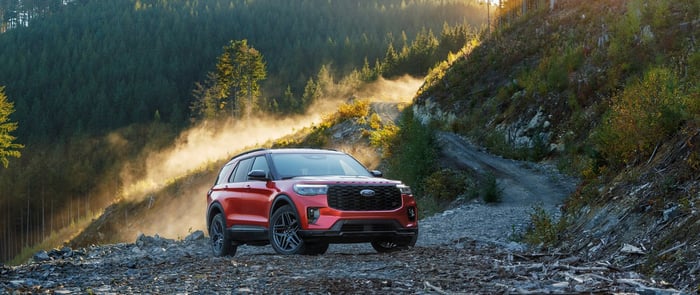 Reliable red Ford Explorer parked in a trail in the mountains, with estimated fuel economy of 21 mpg in the city and 28 mpg on the highway.