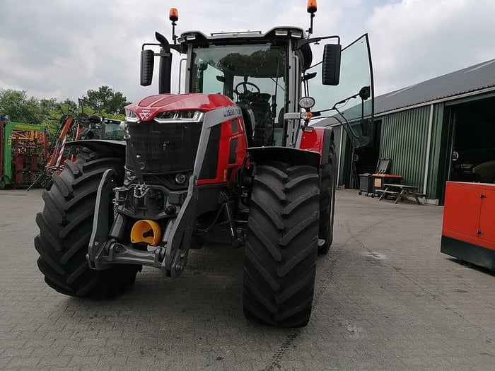 Massey Ferguson 8S Series parked in an agricultural setting with other farm equipment.