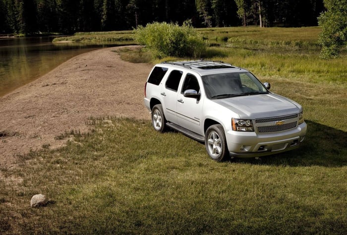 White Chevy Tahoe, with reliability score 3.5 out of 5 and third row seats, parked in front of a creek.