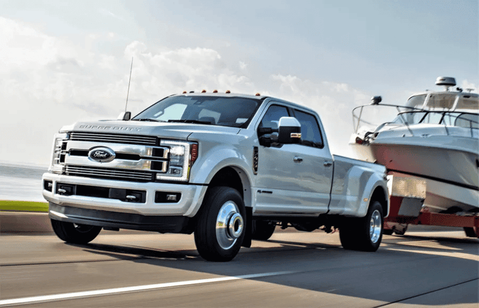 Silver Ford Super Duty pickup, with a boat in tow.