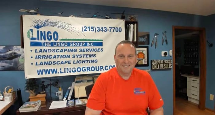 Gavin Lingo in the office, sitting in front of a company sign.