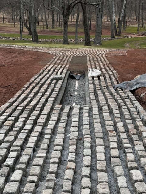 Lingo adding cobblestone to a client's yard.