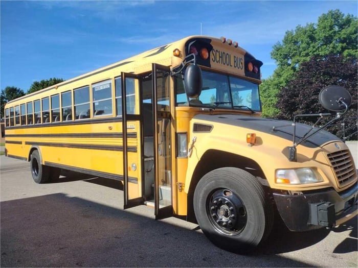A yellow school bus with its doors open, facing right.