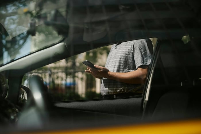 Man checking his mobile device beside a car.