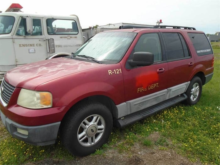 An image of a red SUV, which was once a fire department vehicle and has the department logo painted over.