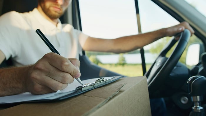 Man making notes on a clipboard inside of a parked vehcile.