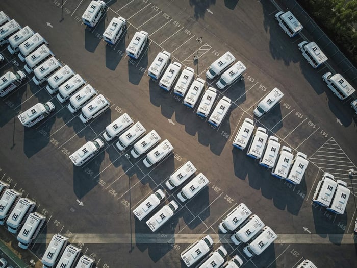 Arial view of parking lot with a fleet of white vehicles.