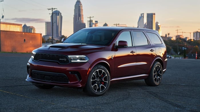 Red Dodge Durango parked on a roof, with a city in the background.