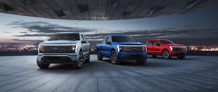 Three Ford F 150s parked at night, overlooking the city.