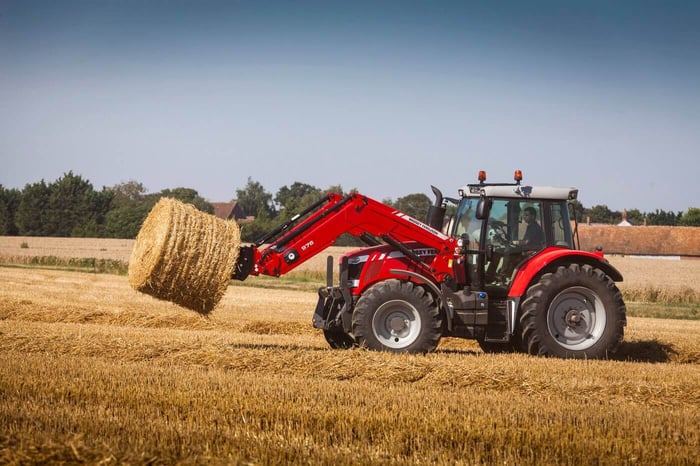 MF 7600 tractor in a hay field making bales.