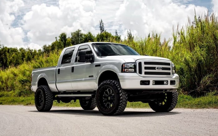 White Powerstroke 7.3 with extended cab on a dirt road.