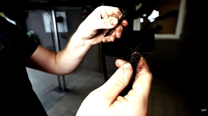 Zahnriemen in Öl - Marvins Hände zeigen einen gerissenen Zahnriemen, der durch das Öl porös wurde