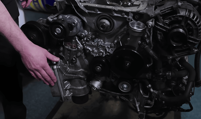 Motor mit Hand, die auf Ölkühler zeigt