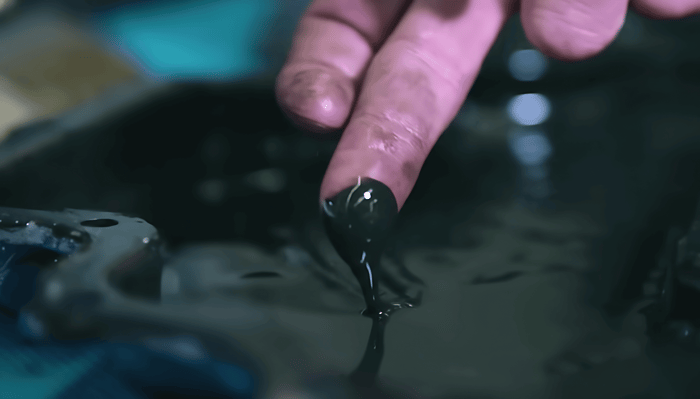 Finger fährt durch Öl beim Ölcheck