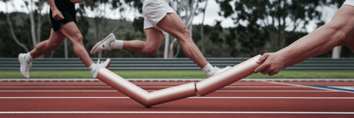 Runners smoothly passing a baton in a relay.
