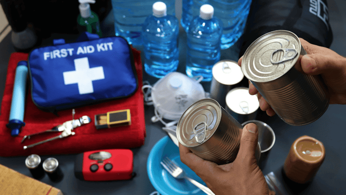 Water, canned food, first-aid supplies, flashlight, and radio arranged for an earthquake emergency kit