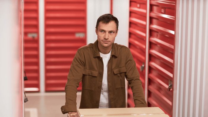Homeowner carrying a box into a self storage unit to reduce garage clutter