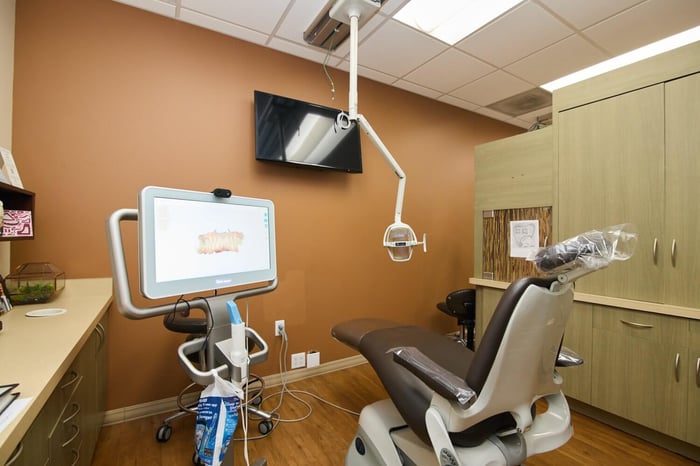 A dental room with a chair and a monitor