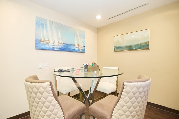 A room with four chairs and a glass table