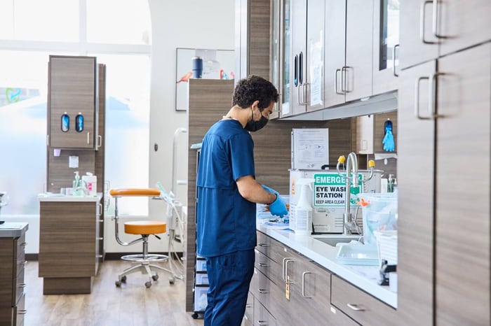 Dental staff member preparing instruments at a clean workstation inside a modern dental clinic.