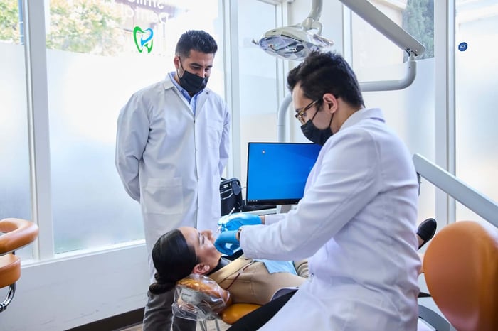 Two person talking to a patient lying on a dental chair